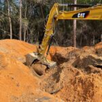 An excavator clearing land in a forested area.